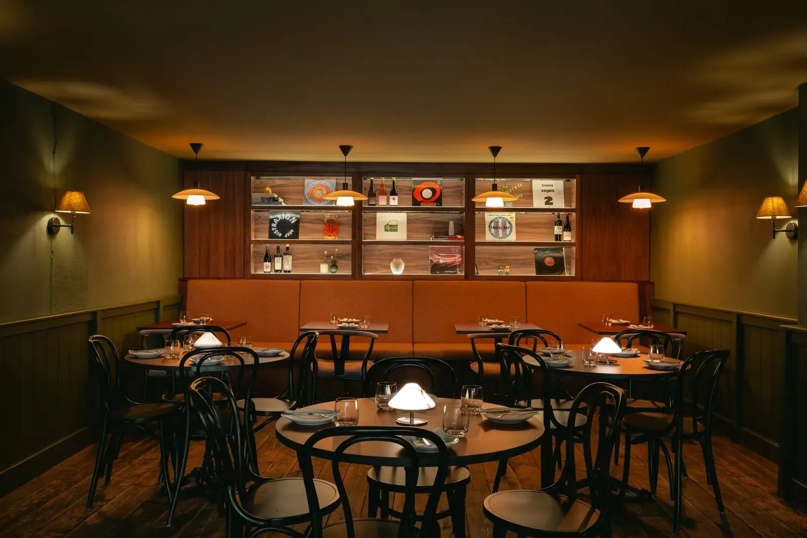 Round tables and bentwood chairs in the back room, wall sconces low and warm.